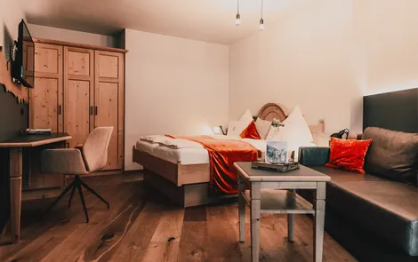 Good Life Cozy hotel room with wooden floor, double bed, sofa, and desk with chair
